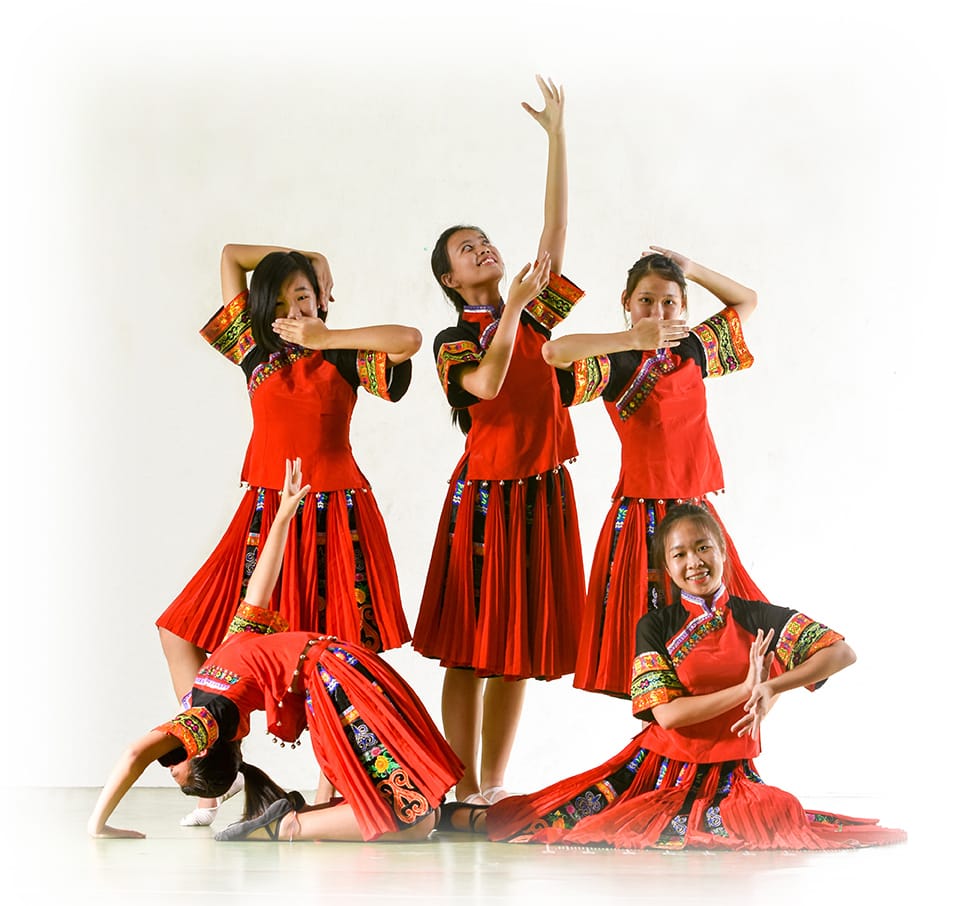 Five young women in red and black embroidered traditional costumes performing coordinated dance poses.